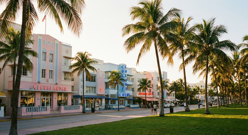 Ocean Drive in South Beach Miami at golden hour with pastel Art Deco hotel facades, neon signs glowing, coconut palm trees, and Lummus Park greenery